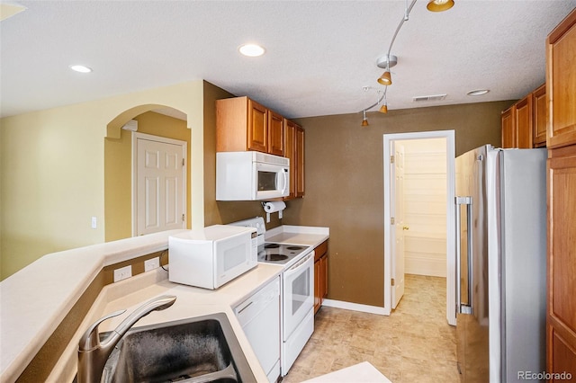 9311 Amison Cir Unit 204, Parker, CO 80134 - kitchen with white appliances, brown cabinets, light countertops, recessed lighting, and arched walkways