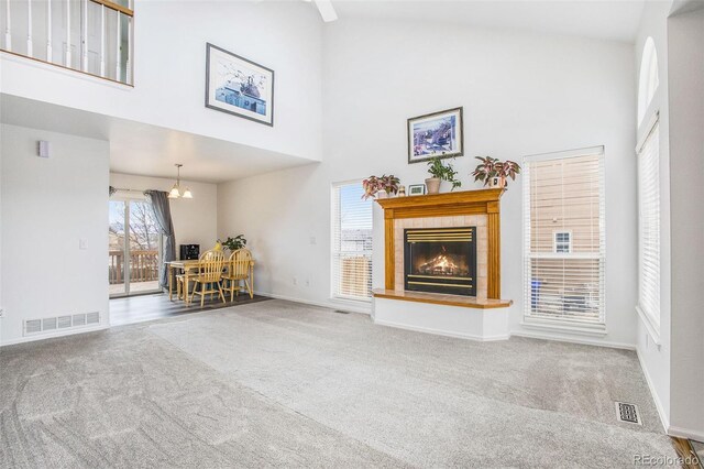2870 Harrisburg Way, Colorado Springs, CO 80922 - carpeted living room featuring baseboards, high vaulted ceiling, a tiled fireplace, and visible vents