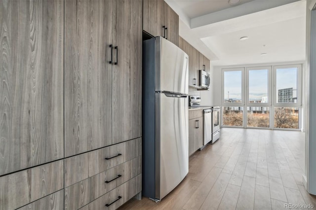 kitchen with stainless steel appliances, light wood-style floors, modern cabinets, and light countertops