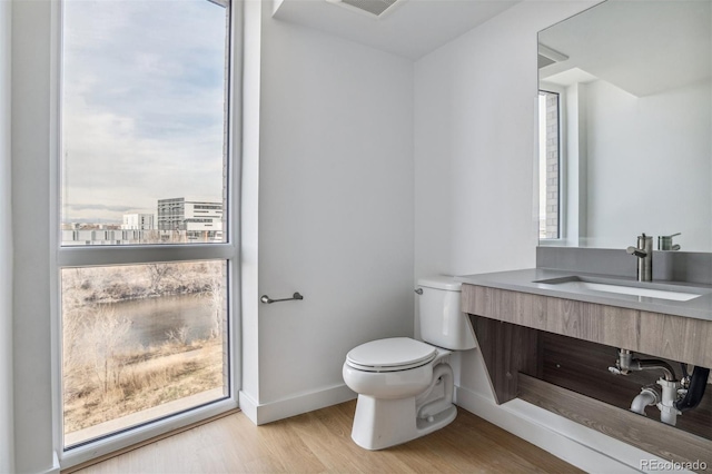 bathroom with vanity, wood finished floors, visible vents, baseboards, and toilet