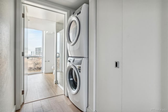 washroom with stacked washer / dryer, laundry area, and light wood-style floors