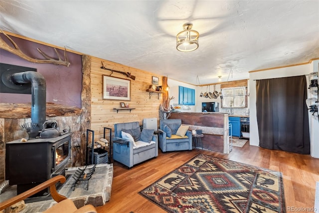 living room featuring hardwood / wood-style flooring, wood walls, a textured ceiling, and a wood stove