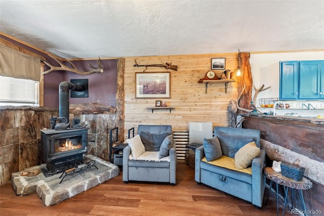 living room featuring wood walls, wood-type flooring, and a wood stove