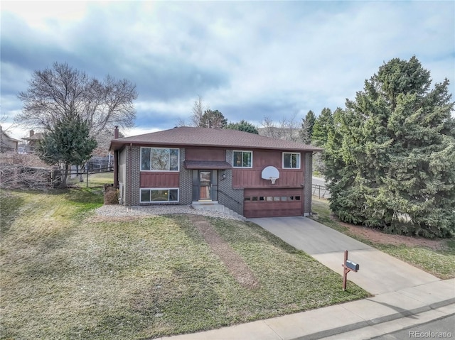 raised ranch with a front lawn, concrete driveway, an attached garage, brick siding, and a chimney