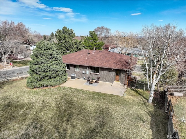 rear view of property with a patio area, a lawn, a shingled roof, and brick siding