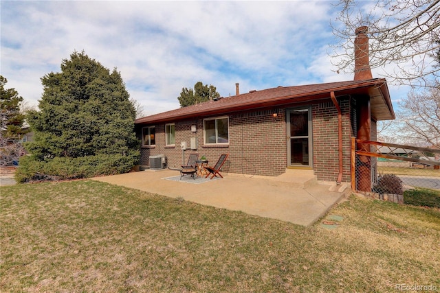 back of property featuring brick siding, a patio area, a lawn, and central AC