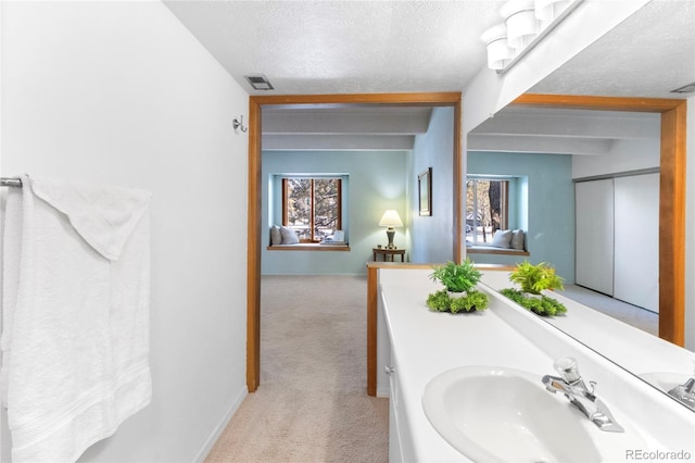 bathroom featuring a textured ceiling, vanity, and beam ceiling