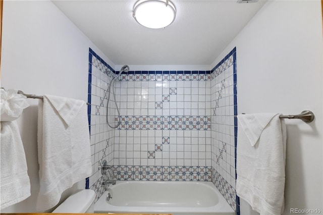 bathroom with toilet and tiled shower / bath