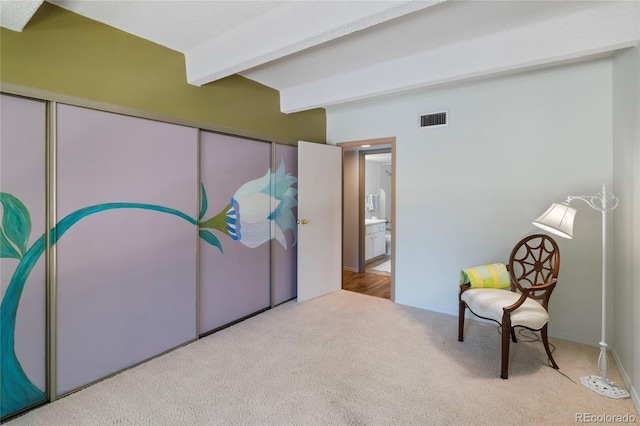 living area featuring beam ceiling and light colored carpet