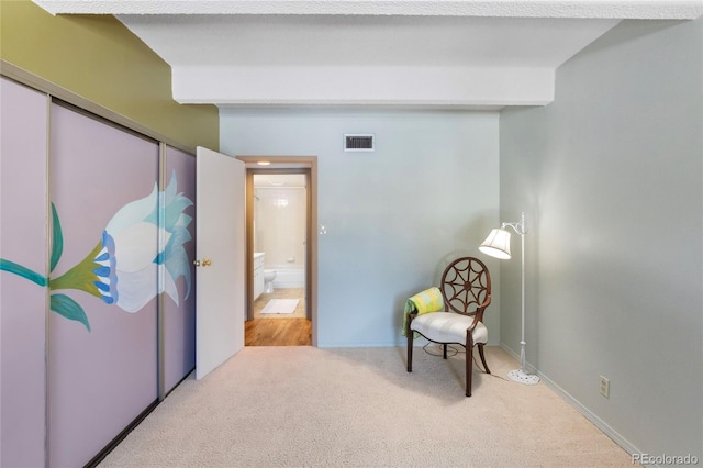 sitting room featuring beam ceiling and light colored carpet