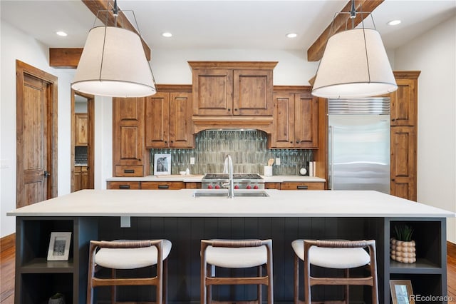 kitchen featuring open shelves, decorative backsplash, brown cabinetry, a sink, and built in refrigerator