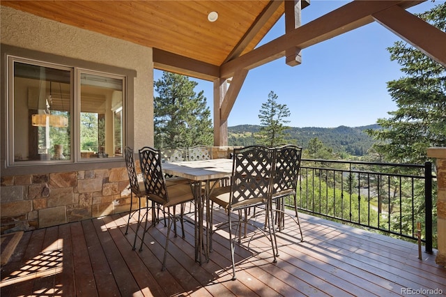 wooden terrace with outdoor dining area and a mountain view