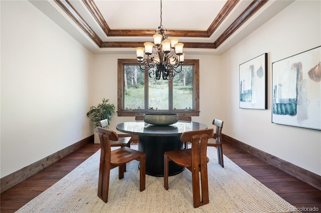 dining room featuring ornamental molding, a tray ceiling, an inviting chandelier, and hardwood / wood-style flooring