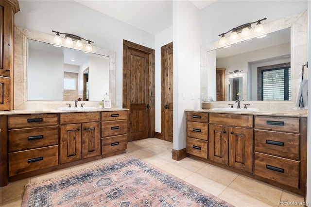 full bathroom featuring tile patterned flooring, baseboards, two vanities, and a sink