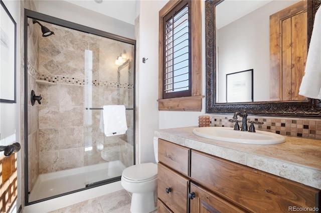 bathroom with vanity, backsplash, a shower stall, and toilet