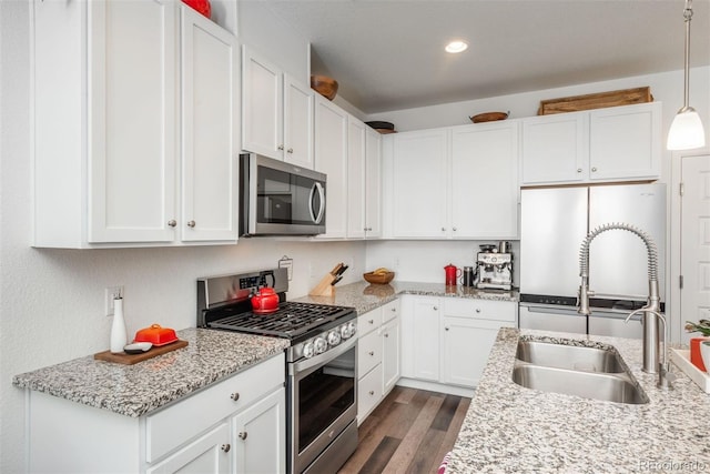 9250 Garnett Way Unit D, Arvada, CO 80007 - kitchen with appliances with stainless steel finishes, white cabinets, dark wood-style floors, hanging light fixtures, and recessed lighting