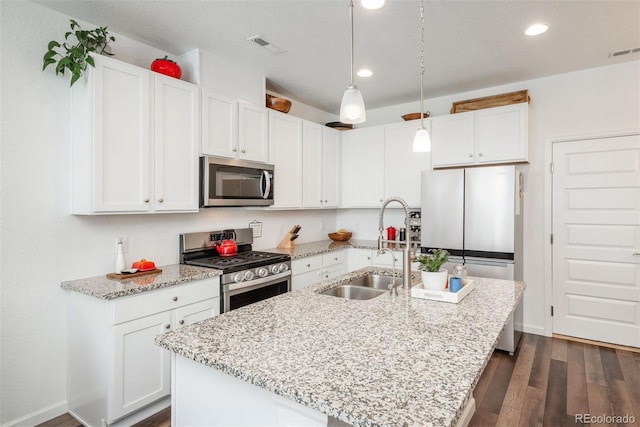 9250 Garnett Way Unit D, Arvada, CO 80007 - kitchen featuring stainless steel appliances, dark wood-style flooring, a center island with sink, white cabinets, and light stone counters