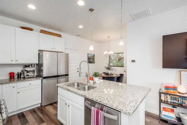 9250 Garnett Way Unit D, Arvada, CO 80007 - kitchen with stainless steel appliances, dark wood-style floors, a chandelier, white cabinetry, and light stone countertops