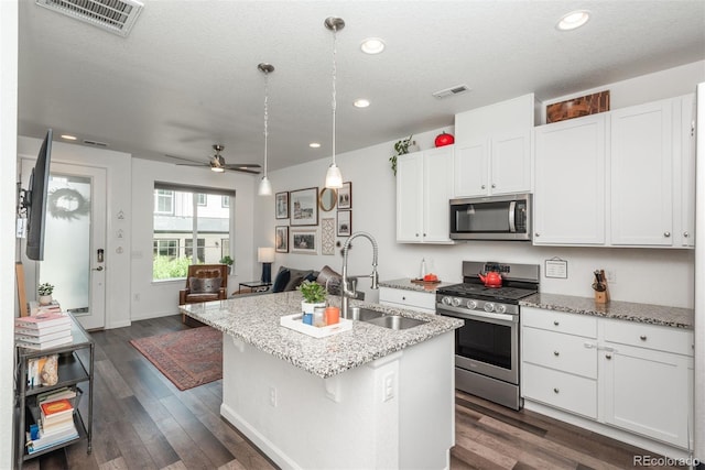 9250 Garnett Way Unit D, Arvada, CO 80007 - kitchen with stainless steel appliances, a center island with sink, dark wood-style flooring, light stone countertops, and recessed lighting