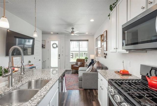 9250 Garnett Way Unit D, Arvada, CO 80007 - kitchen featuring appliances with stainless steel finishes, dark wood finished floors, white cabinetry, recessed lighting, and light stone counters