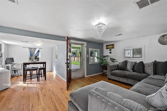 living room featuring light hardwood / wood-style floors, a textured ceiling, and a chandelier