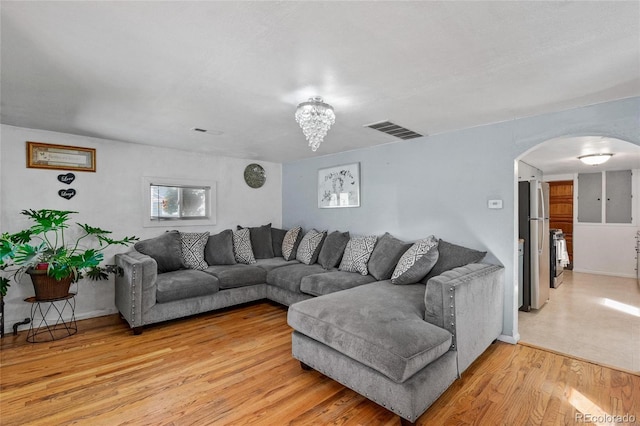 living room with a notable chandelier and light wood-type flooring