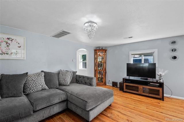 living room featuring wood-type flooring, a textured ceiling, and an inviting chandelier