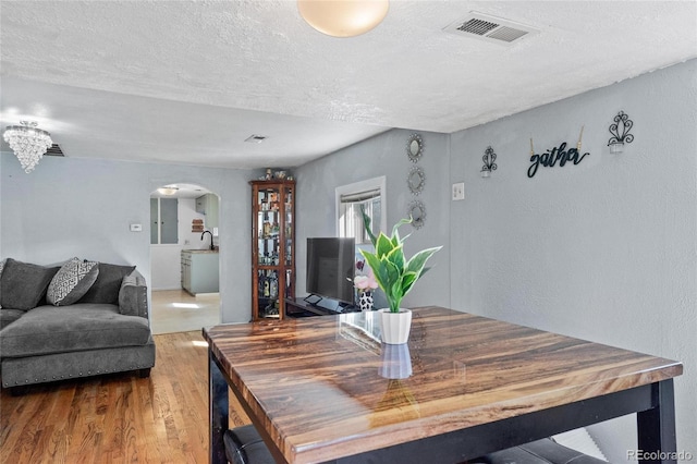 dining area featuring wood-type flooring and a textured ceiling