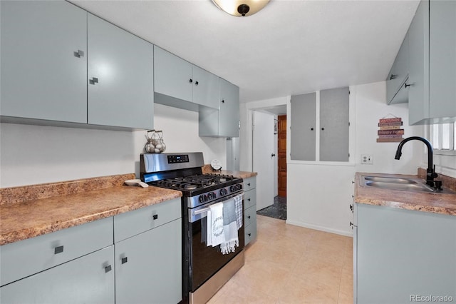 kitchen featuring light tile patterned floors, stainless steel range with gas cooktop, and sink