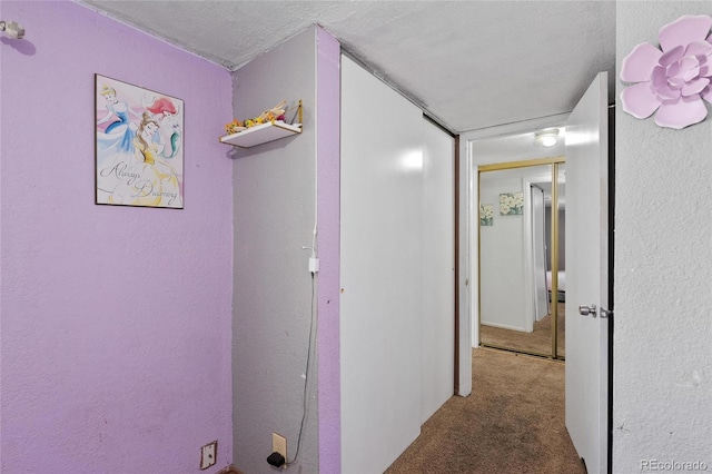 hallway featuring carpet flooring and a textured ceiling