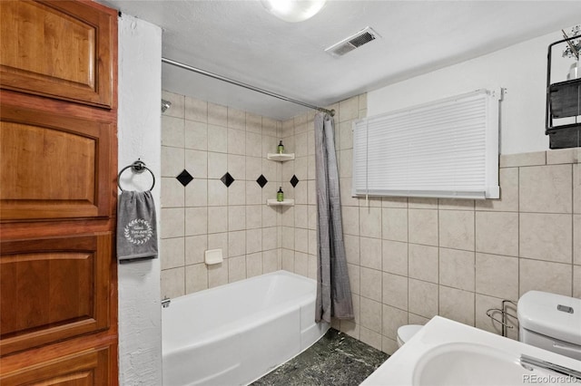 bathroom with shower / bath combo with shower curtain, tile walls, and toilet