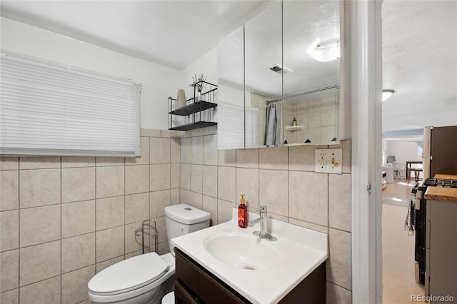 bathroom featuring vanity, tile walls, and toilet