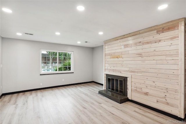 unfurnished living room with light hardwood / wood-style floors and wooden walls