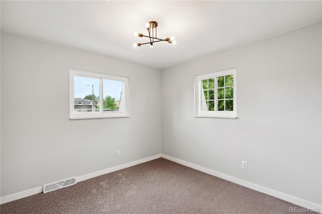 empty room with an inviting chandelier and carpet floors