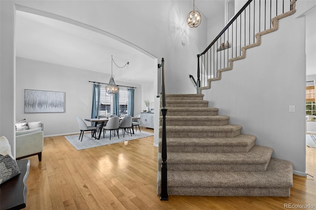 2880 Breezy Ln, Castle Rock, CO 80109 - staircase with a chandelier, wood finished floors, baseboards, a high ceiling, and arched walkways