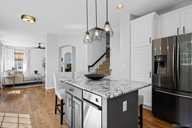 2880 Breezy Ln, Castle Rock, CO 80109 - kitchen featuring stainless steel fridge with ice dispenser, a breakfast bar, arched walkways, a ceiling fan, and a kitchen island