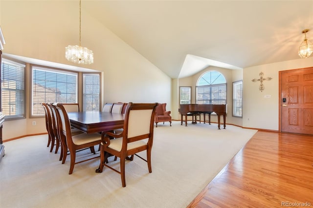 dining space with an inviting chandelier, light colored carpet, baseboards, and high vaulted ceiling