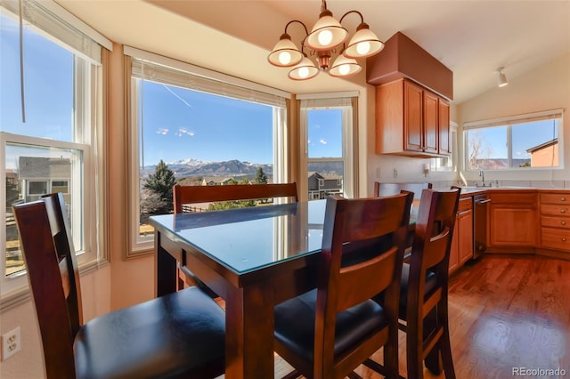 dining area featuring an inviting chandelier, vaulted ceiling, dark wood finished floors, and a mountain view