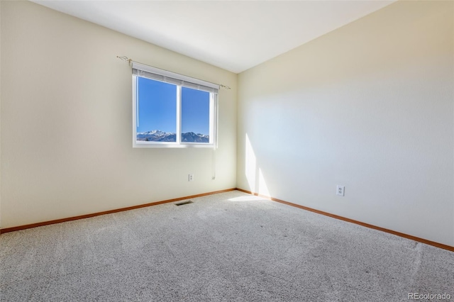 unfurnished room with carpet, visible vents, and baseboards