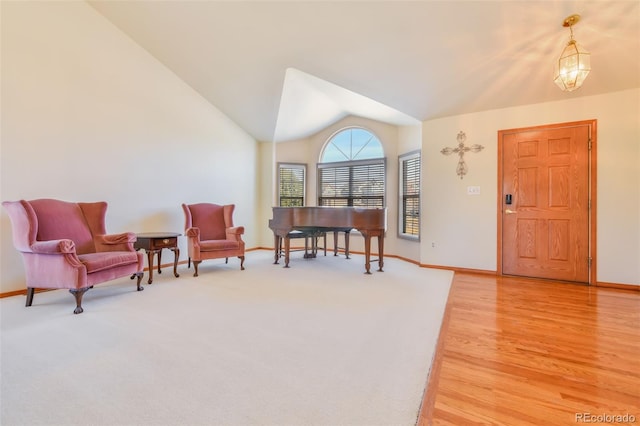 entryway with baseboards, lofted ceiling, a notable chandelier, and light wood-style flooring