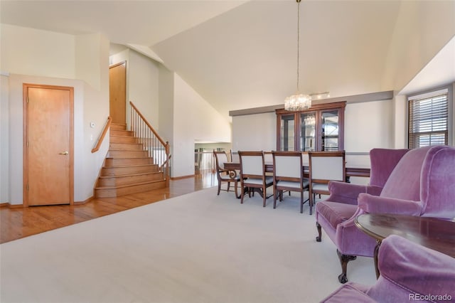 living area with baseboards, a chandelier, stairway, wood finished floors, and high vaulted ceiling