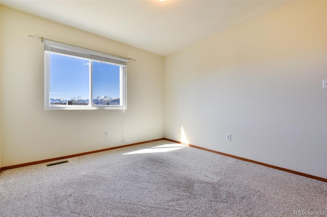 spare room with carpet, visible vents, and baseboards