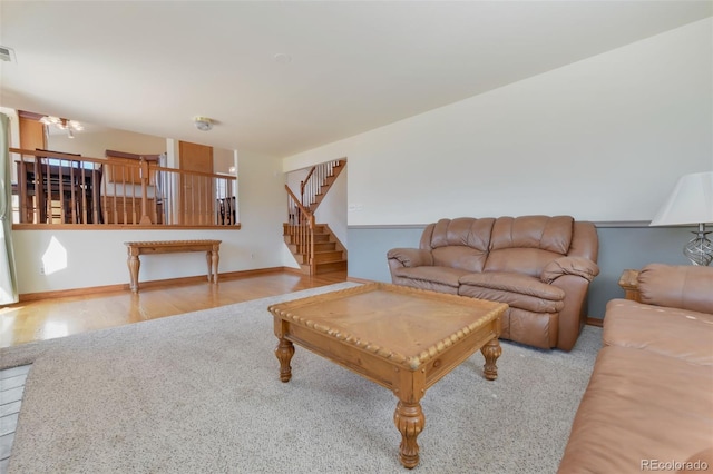 living room featuring stairway, visible vents, baseboards, and wood finished floors