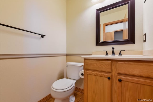 half bathroom featuring toilet, vanity, and wood finished floors