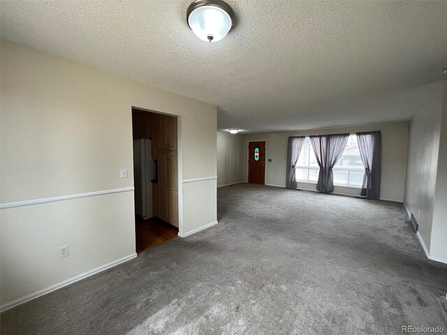 unfurnished room featuring a textured ceiling and dark carpet