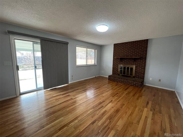 unfurnished living room featuring a fireplace, hardwood / wood-style floors, and a textured ceiling