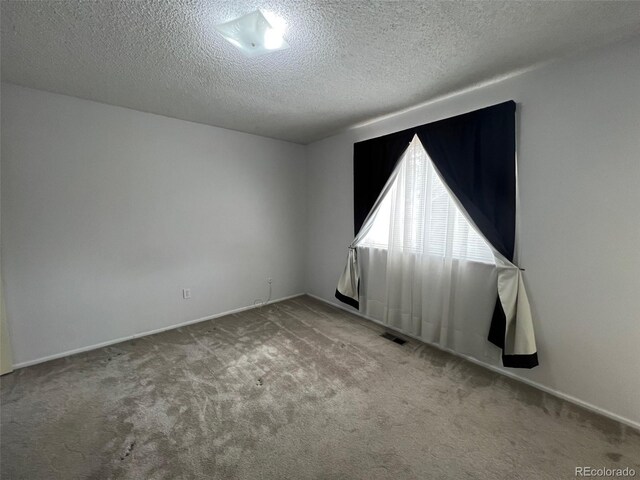 unfurnished room featuring light colored carpet and a textured ceiling