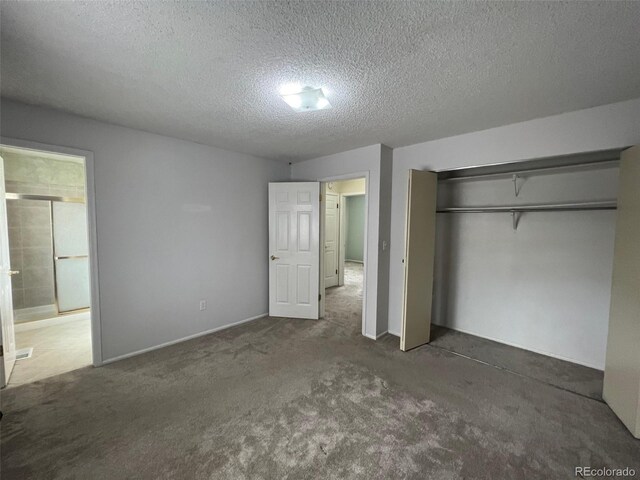 unfurnished bedroom featuring a textured ceiling, dark carpet, and a closet