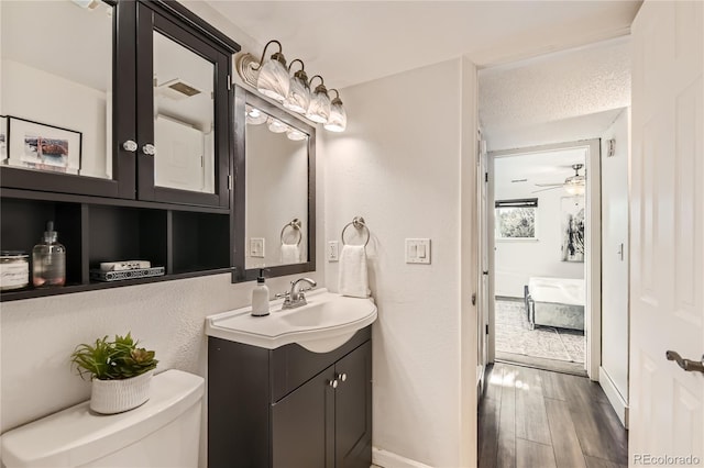 bathroom with hardwood / wood-style flooring, ceiling fan, vanity, a textured ceiling, and toilet