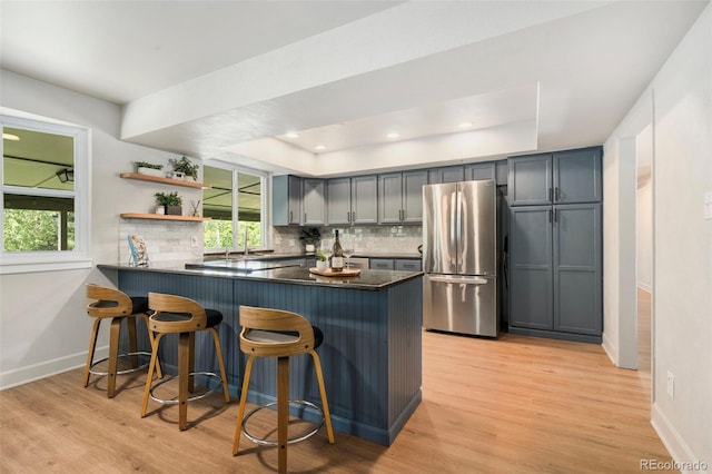 1420 W Ridge Rd, Littleton, CO 80120 - kitchen with freestanding refrigerator, a tray ceiling, dark countertops, a peninsula, and a breakfast bar area